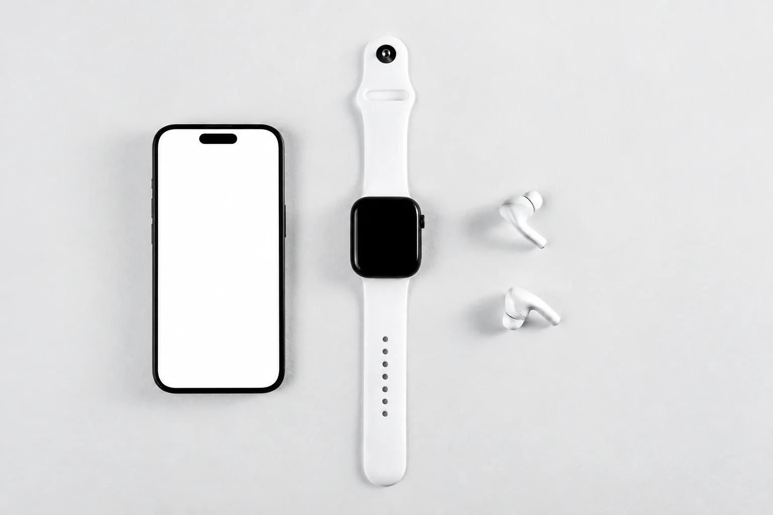 A phone, white smartwatch and two earbuds arranged on a light surface.