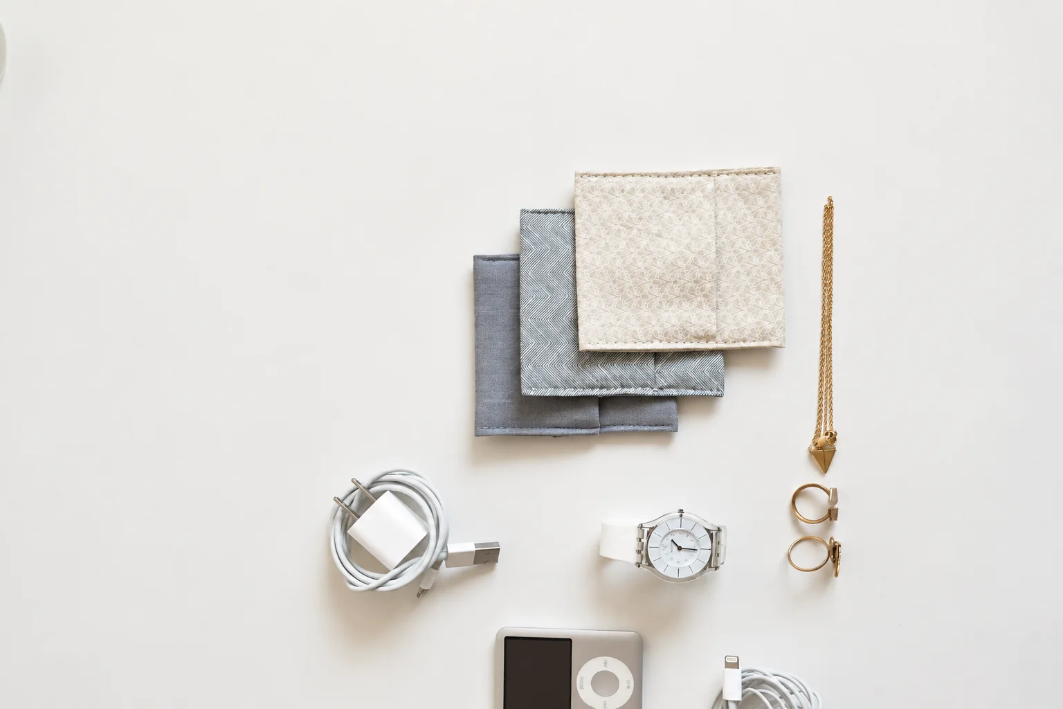 Small fabric pouches, charging cables and personal accessories on a light surface.